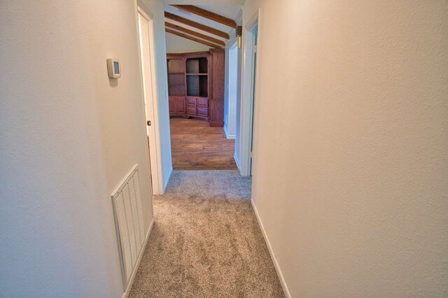 hall featuring lofted ceiling with beams, carpet flooring, baseboards, and visible vents