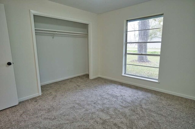 unfurnished bedroom featuring a closet, baseboards, and carpet