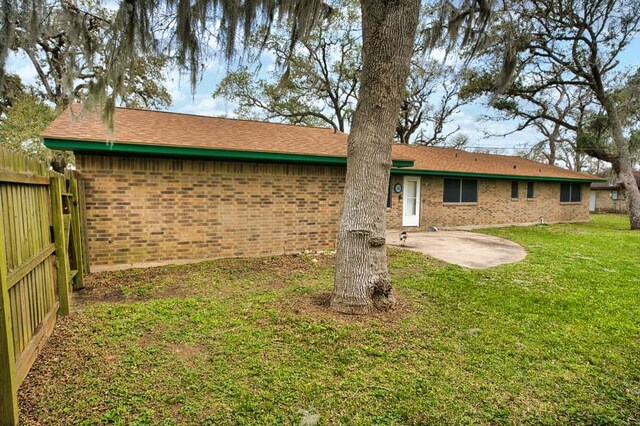 back of property featuring brick siding, a patio area, fence, and a lawn