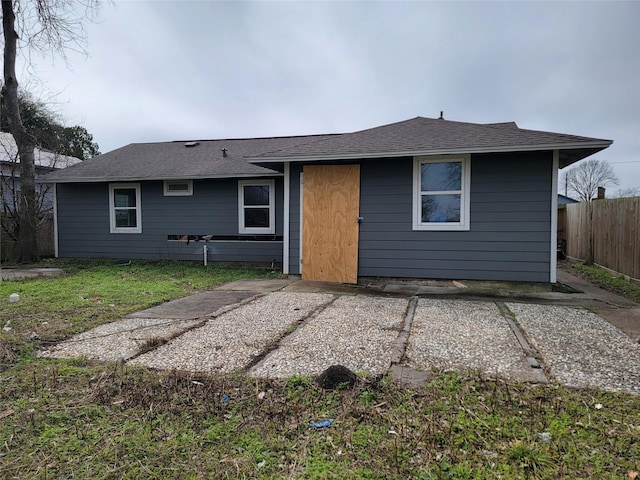 rear view of property with roof with shingles and fence