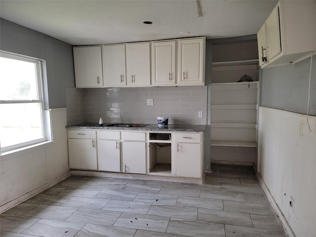 kitchen with decorative backsplash, open shelves, white cabinets, and stone countertops