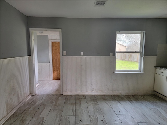 empty room with visible vents and wainscoting