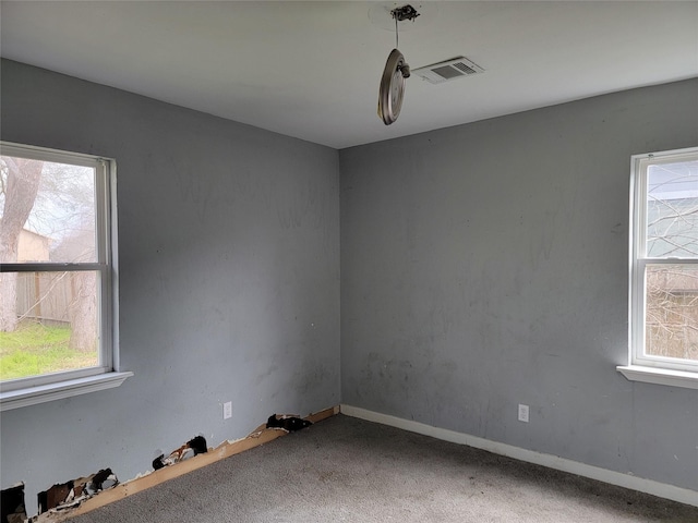 carpeted empty room featuring baseboards and visible vents