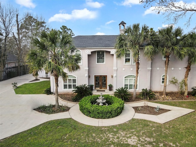 view of front of house featuring french doors, driveway, a front yard, and stucco siding