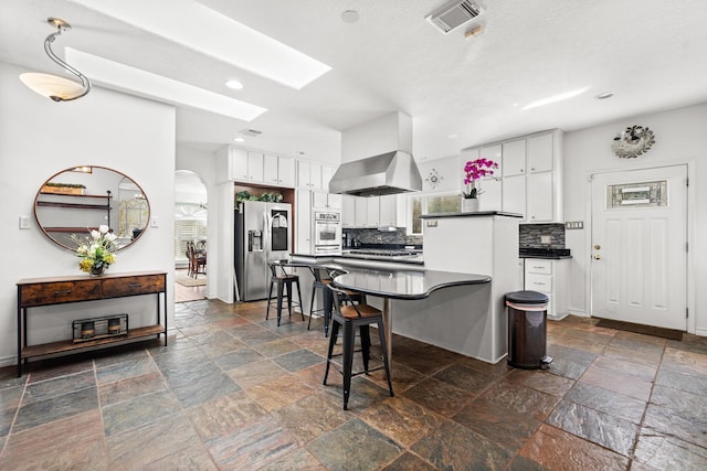 kitchen with stone tile flooring, stainless steel appliances, visible vents, and dark countertops