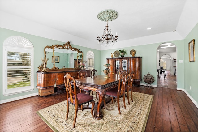 dining area featuring arched walkways, dark wood finished floors, baseboards, a notable chandelier, and recessed lighting