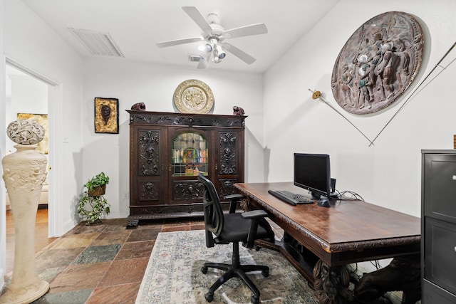 office space with stone tile floors, baseboards, a ceiling fan, and visible vents