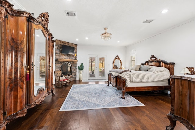 bedroom with a stone fireplace, hardwood / wood-style floors, visible vents, and recessed lighting