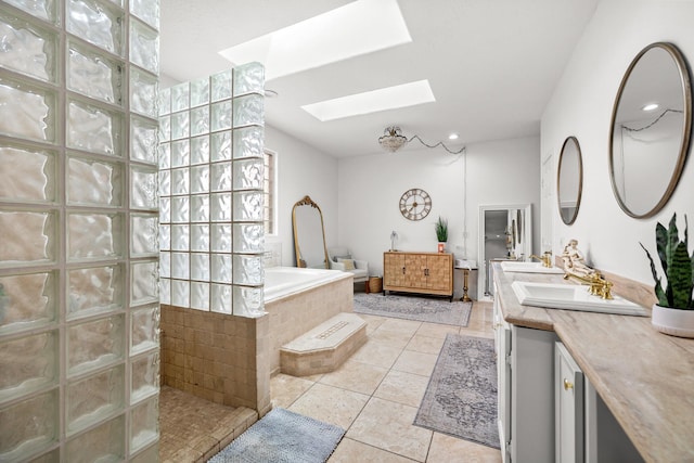 full bathroom with tile patterned floors, vanity, a walk in shower, a skylight, and a garden tub
