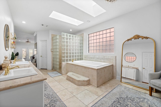 bathroom featuring tile patterned floors, a sink, a skylight, a bath, and recessed lighting