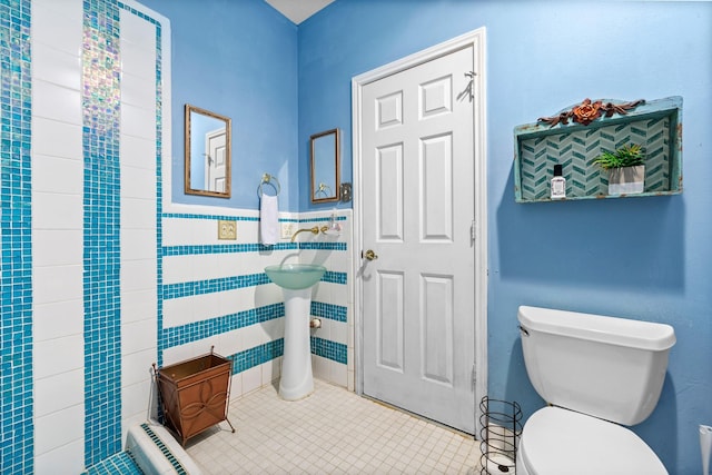 bathroom featuring tile walls, toilet, a wainscoted wall, and tile patterned floors