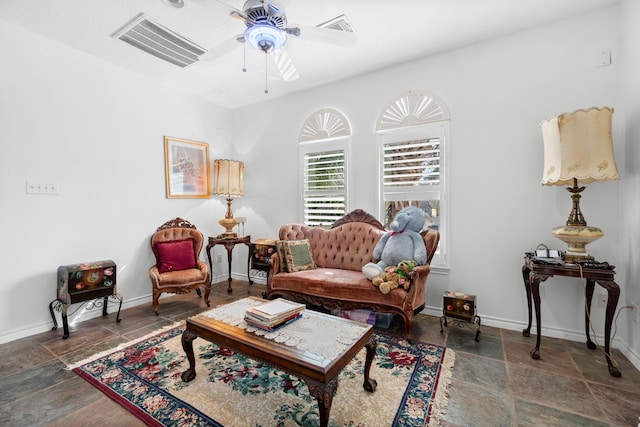 sitting room featuring stone tile flooring, baseboards, a ceiling fan, and visible vents