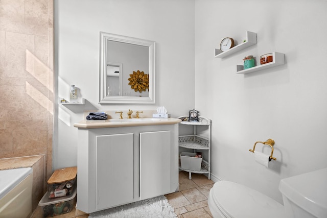 bathroom featuring stone tile flooring, baseboards, vanity, and toilet