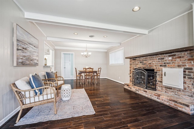 living area with a brick fireplace, beamed ceiling, ornamental molding, wood finished floors, and a notable chandelier