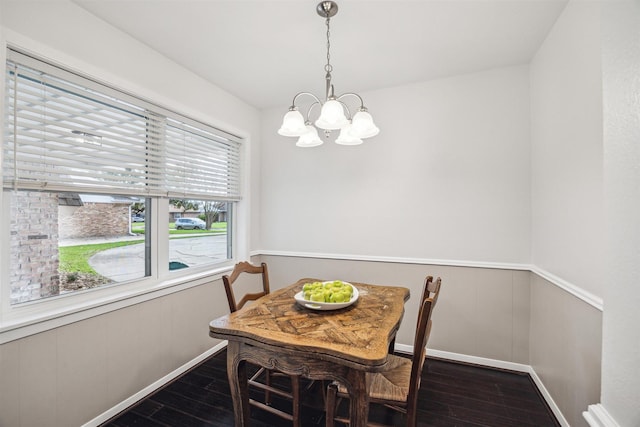 dining space with dark wood-type flooring, baseboards, a wainscoted wall, and a chandelier