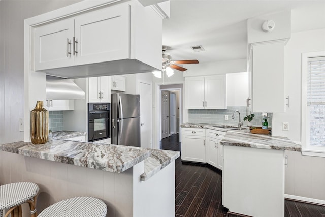 kitchen featuring oven, a peninsula, freestanding refrigerator, dark wood-style floors, and a sink