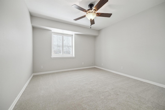 carpeted spare room featuring a ceiling fan and baseboards