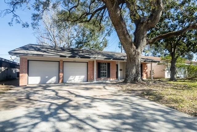 single story home featuring brick siding, driveway, and an attached garage