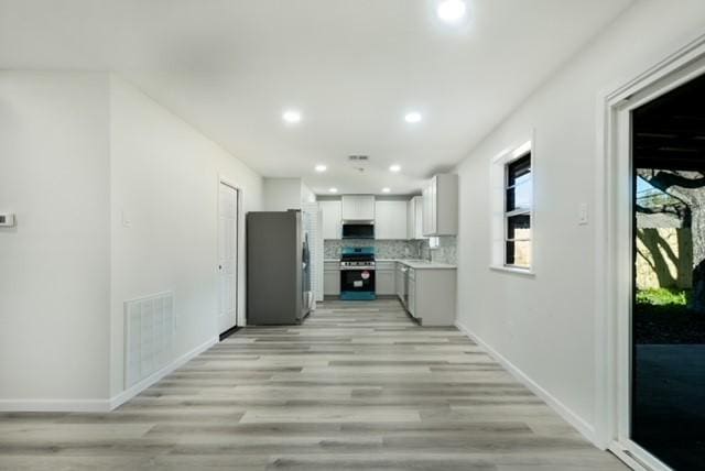 kitchen featuring visible vents, under cabinet range hood, light countertops, decorative backsplash, and appliances with stainless steel finishes