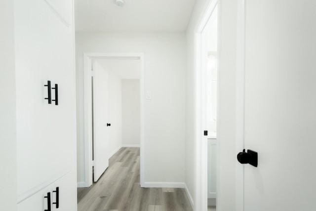 hall featuring baseboards and light wood-style flooring