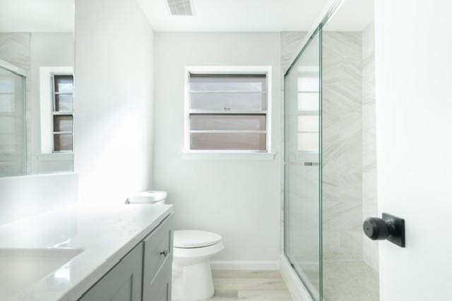 bathroom featuring visible vents, baseboards, toilet, a stall shower, and vanity