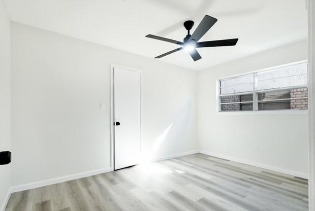 unfurnished room featuring a ceiling fan, baseboards, and wood finished floors