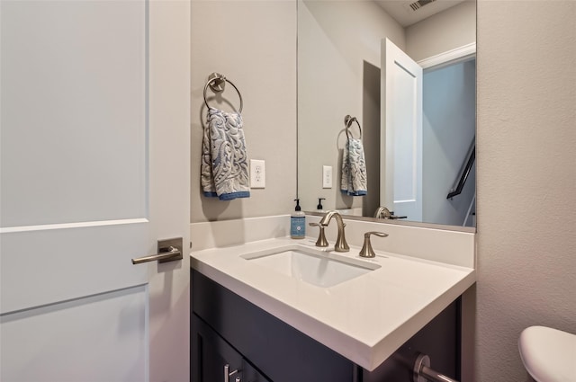 bathroom featuring vanity, toilet, and visible vents