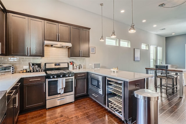 kitchen with under cabinet range hood, decorative backsplash, stainless steel appliances, and dark wood-style floors