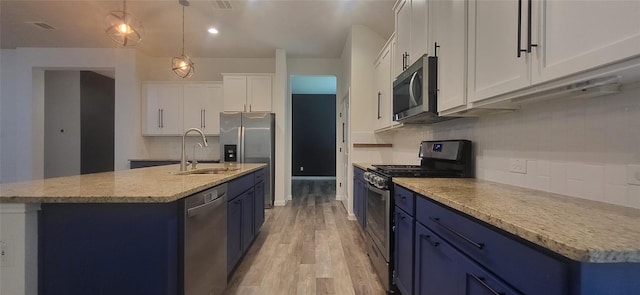 kitchen featuring decorative backsplash, blue cabinets, appliances with stainless steel finishes, and a sink