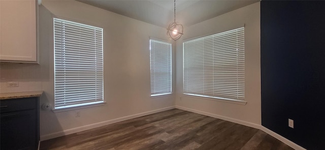 unfurnished dining area featuring baseboards and dark wood-style floors