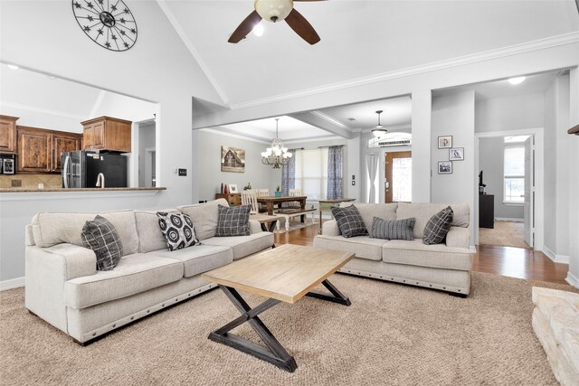 living room featuring high vaulted ceiling, ornamental molding, ceiling fan with notable chandelier, wood finished floors, and baseboards