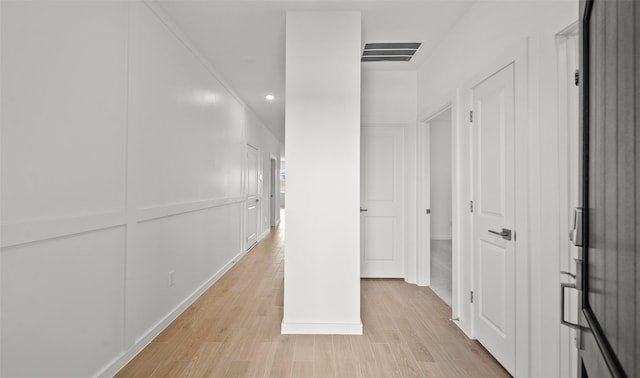 hall with recessed lighting, visible vents, light wood-style floors, and a decorative wall