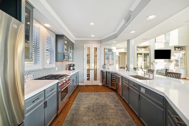 3515 Jolly Roger Cir, Galveston, TX 77554 - kitchen with stainless steel appliances, a sink, dark wood-type flooring, light countertops, and glass insert cabinets