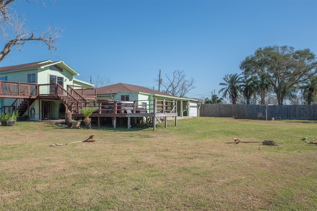 view of yard featuring an attached garage, stairs, a deck, and fence