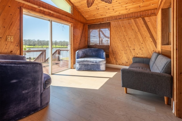 living room with wood walls, wood-type flooring, ceiling fan, and vaulted ceiling