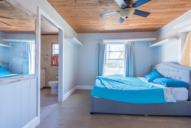 bedroom featuring baseboards, ceiling fan, wood ceiling, ensuite bathroom, and wood finished floors