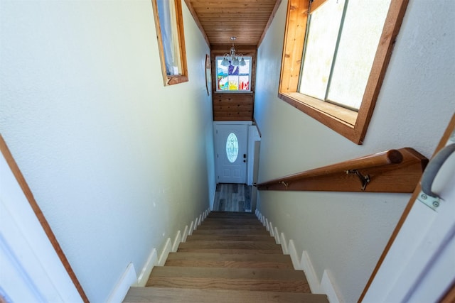 staircase featuring a chandelier, wooden ceiling, and wood finished floors