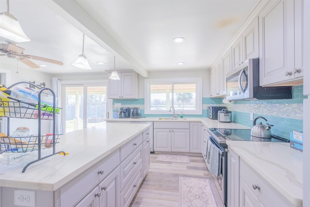 kitchen with tasteful backsplash, a healthy amount of sunlight, stainless steel appliances, and a sink