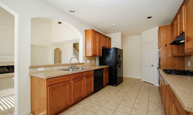 kitchen with under cabinet range hood, black appliances, tasteful backsplash, and a sink