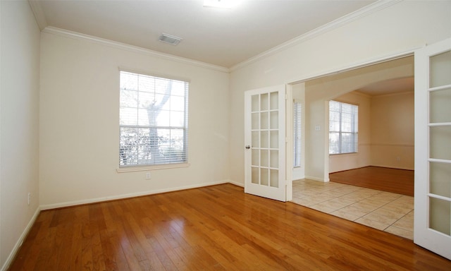 empty room with arched walkways, visible vents, french doors, and wood-type flooring