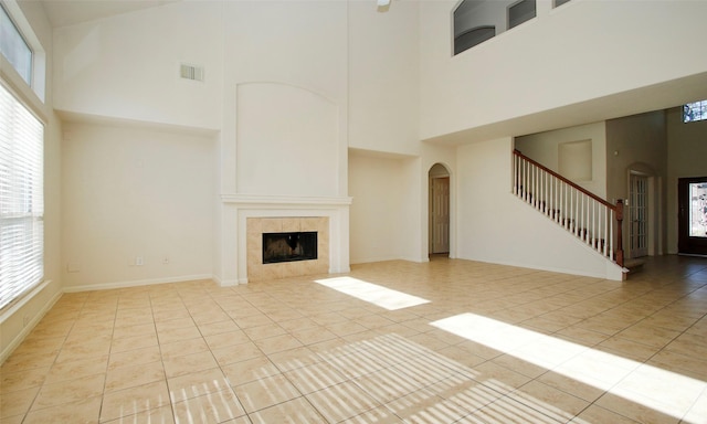 unfurnished living room featuring visible vents, arched walkways, light tile patterned flooring, and stairway