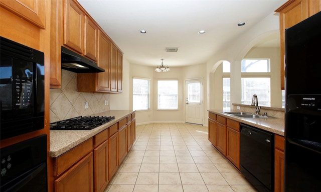 kitchen featuring visible vents, under cabinet range hood, light tile patterned floors, black appliances, and a sink