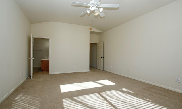 unfurnished bedroom featuring light carpet, connected bathroom, baseboards, and vaulted ceiling