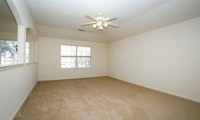 spare room featuring light carpet, visible vents, ceiling fan, and baseboards