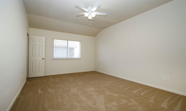 empty room featuring a ceiling fan, vaulted ceiling, carpet, and baseboards