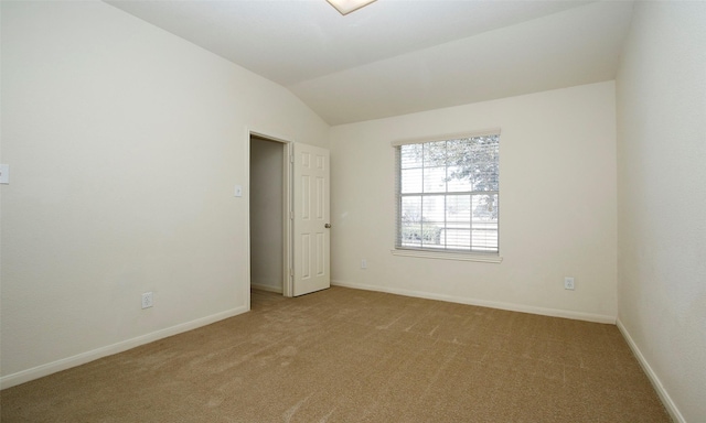 empty room with lofted ceiling, baseboards, and light carpet