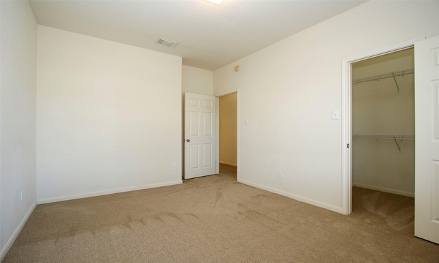 unfurnished bedroom featuring a spacious closet, visible vents, baseboards, carpet flooring, and a closet