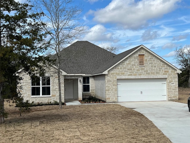 view of front facade featuring driveway, a shingled roof, and a garage