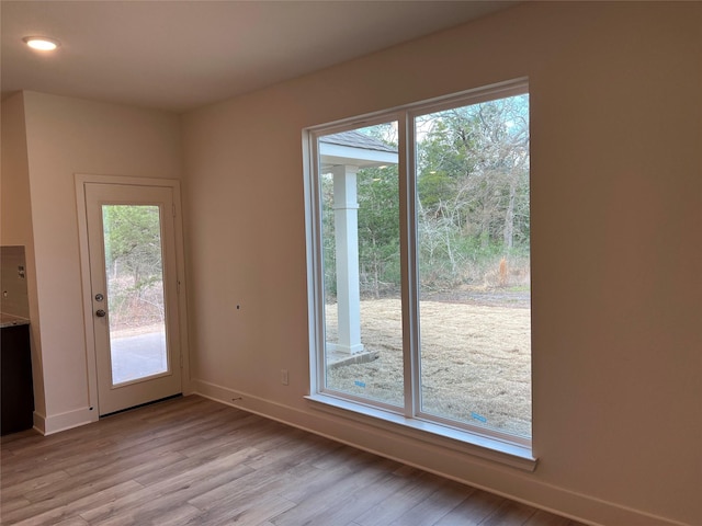 entryway with baseboards, a healthy amount of sunlight, and light wood-style flooring