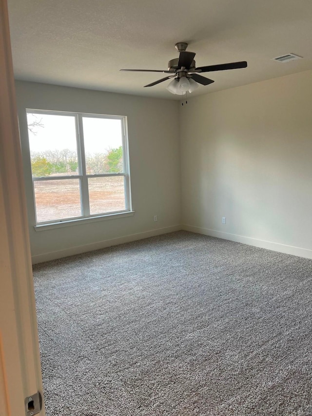 carpeted empty room featuring visible vents, ceiling fan, and baseboards